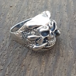 bague argent 925 tete de mortavec en son centre un crane et de chaque coté des griffes qui viennent enlacé celui-ci .