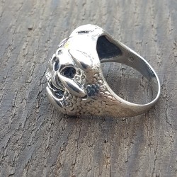 bague argent 925 tete de mortavec en son centre un crane et de chaque coté des griffes qui viennent enlacé celui-ci .